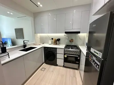 a kitchen with white cabinets and a stove and a dishwasher at Chic Jvc 1br Balcony, Pool And Parking in Dubai