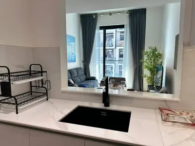 a kitchen with a sink and a living room at Chic Jvc 1br Balcony, Pool And Parking in Dubai