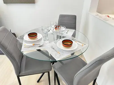 a glass table with chairs and plates and glasses at Chic Jvc 1br Balcony, Pool And Parking in Dubai