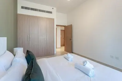 a large white bed with two blue towels on it at HAVN - 1 Bedroom in Azizi Park Avenue, Meydan in Dubai