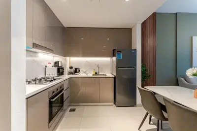 a kitchen with stainless steel appliances and a table at HAVN - 1 Bedroom in Azizi Park Avenue, Meydan in Dubai