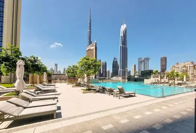 a pool with chaise lounge chairs and a city skyline at Premium 3BR l Office with Burj Khalifa & Fountain Views in Dubai