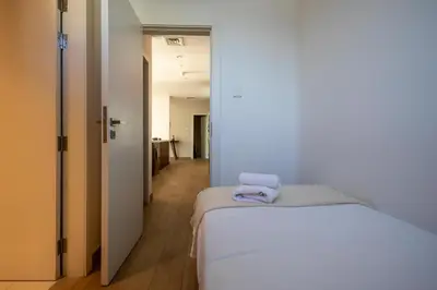 a bedroom with a white bed and a hallway at HiGuests - Experience Coastal Elegance at La Rive 2 in La Mer in Dubai