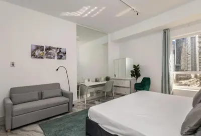 a bedroom with a bed and a chair and a mirror at Ahlan Premium Luxury Marina Cityview JBR in Dubai
