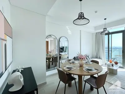 a white living room with a table and chairs at Luxury One Bedroom with Balcony & partial Burj Khalifa View in Dubai