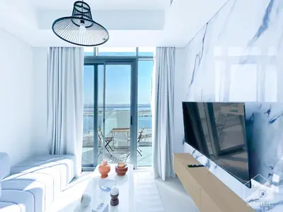 a living room with a white couch and a tv at Luxury One Bedroom with Balcony & partial Burj Khalifa View in Dubai