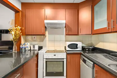 a kitchen with wooden cabinets and a stove top oven at JBR Beach 2Bed Apartment with Full Marina View in Dubai