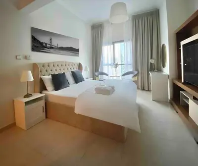 a white bedroom with a large bed and a television at Stylist Studio in Marina near beach and Metro Z1103 in Dubai