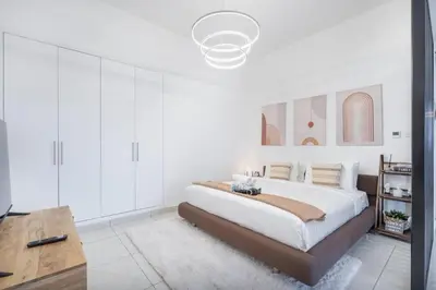 a white bedroom with a large bed and a table at SuCasa in Dubai