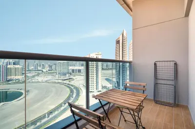a balcony with a wooden table and two chairs at Stunning studio at sports city in Dubai