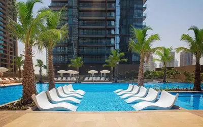 a swimming pool with white chairs and palm trees at SOLARTE Luxe - Marina Gate - Spectacular Pools with Marina Views in Dubai
