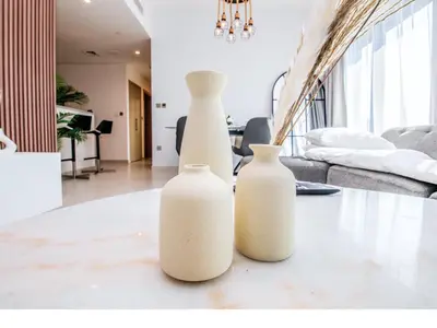 three white vases sitting on a table in a living room at BURJ ROYALE - Full Burj Khalifa & Fountain Views - LUXE Apartment in Dubai