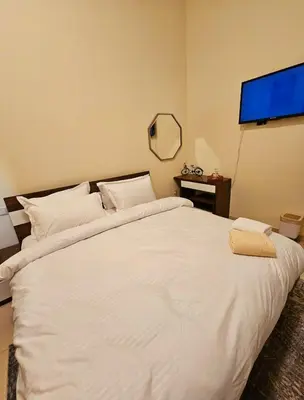 a bedroom with a white bed with a flat screen tv at Room with bathroom near beach walk la mer beach Oima leasing property in Dubai