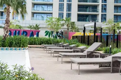 a row of lounge chairs in front of a building at Limited Time Offer Tranquil 1BR in Business Bay by Deluxe Holiday Homes in Dubai