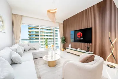 a living room with white furniture and a flat screen tv at Exclusive Beachfront 2 Bed with Pool & Palm View in Dubai