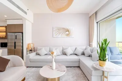 a living room with a white couch and a table at Exclusive Beachfront 2 Bed with Pool & Palm View in Dubai