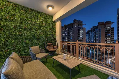 a balcony with a green wall with chairs and tables at Marina Haven I Waterfront I Pool I Gym and Sauna in Dubai