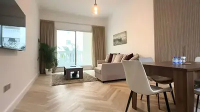 a living room with a table and a couch at Modern 1BR Retreat with Balcony in Vibrant JVC by Bhavan Vacation Homes in Dubai