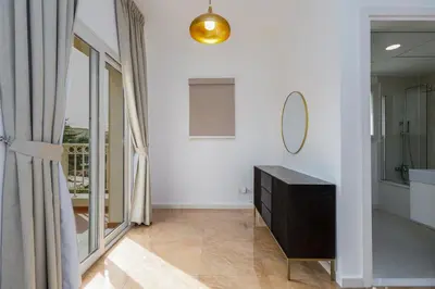 a bathroom with white walls and a mirror and a dresser at Family Friendly - 2BR & Maid's Room in The Springs 10 - Allsopp & Allsopp in Dubai