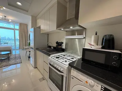 a kitchen with a stove and a microwave at ASHRI Studio in Carson C, Damac Hills 1 in Dubai
