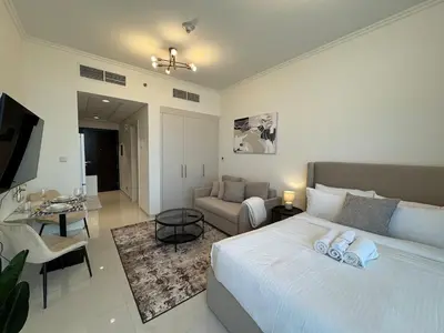 a bedroom with a bed and a living room at ASHRI Studio in Carson C, Damac Hills 1 in Dubai