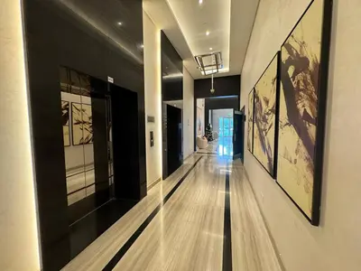 a hallway in a building with paintings on the walls at ASHRI Studio in Carson C, Damac Hills 1 in Dubai