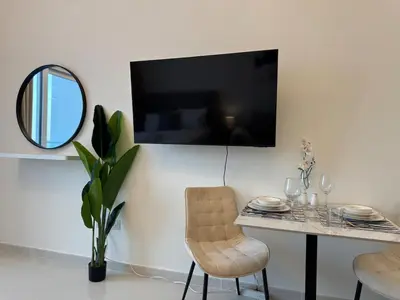 a dining room with a table and a mirror at ASHRI Studio in Carson C, Damac Hills 1 in Dubai
