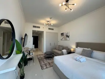 a bedroom with a bed and a living room at ASHRI Studio in Carson C, Damac Hills 1 in Dubai