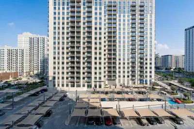 a large white building with cars parked in a parking lot at Comfortable Stylish Haven - Great Community in Dubai
