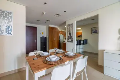 a dining room with a wooden table and white chairs at GuestReady - Magnificent stay with lake view in Dubai