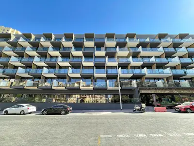 a large building with cars parked in front of it at Stunning 1 br modern luxury residence at JVC in Dubai