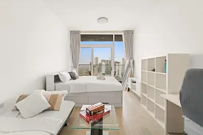 a bedroom with two beds and a couch and a window at Chic JVC Studio in Dubai - Pool, Gym, Free Parking, City Views & Prime Location in Dubai