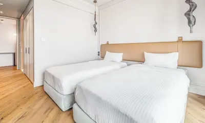 two beds in a room with white walls and wooden floors at 2BR Jumeirah Gate 1, Marina Skyline View in Dubai