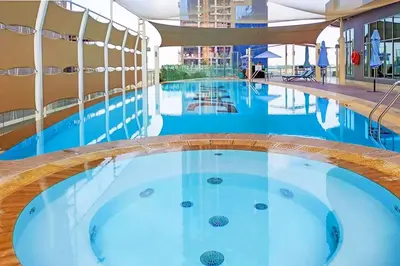 a large swimming pool with blue water in a building at Vserve Stylish Suite 1 BR with Burj Khalifa and Canal view in Dubai