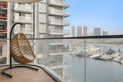 a rattan chair sitting on a balcony overlooking a marina at Silkhaus Seaside 2BDR in Marina Vista Beachfront in Dubai