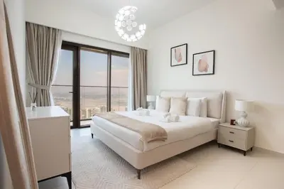 a white bedroom with a bed and a large window at Prime Downtown Location 2BR Apt Burj Royale in Dubai