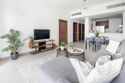 a living room with a gray couch and a kitchen at Frank Porter - Park Gate in Dubai