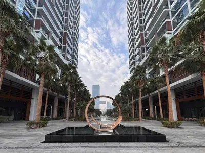 a circular sculpture in front of a building with palm trees at Frank Porter - Park Gate in Dubai