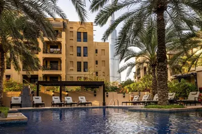 a pool with chairs and palm trees and a building at Maison Privee - Stylish & Spacious Apartment in Downtown Dubai in Dubai