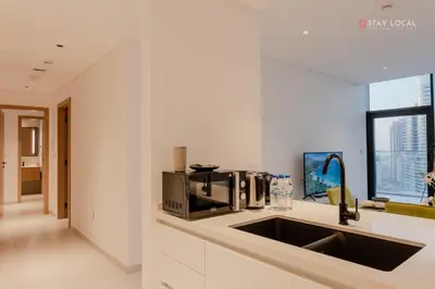 a kitchen with a sink and a microwave on a counter at Experience Iconic Burj Khalifa Views from Your Cozy Getaway with Pool in Dubai