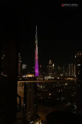 a lit up tower in the city at night at Experience Iconic Burj Khalifa Views from Your Cozy Getaway with Pool in Dubai