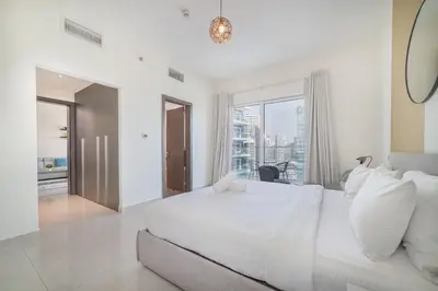 a white bedroom with a large bed and a window at Elegant 1BR with Balcony & Views in Business Bay in Dubai
