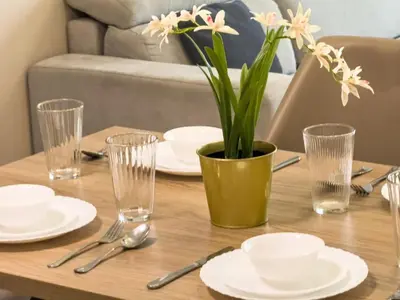 a table with plates and glasses and a vase with flowers at Elegant 1BR with Balcony & Views in Business Bay in Dubai