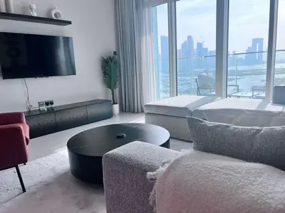 a living room with a tv and a couch and a table at A Luxurious 2 Bedroom Emaar Beachfront Apartment in Palm Jumeirah in Dubai