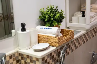 a bathroom counter with a basket of towels and a mirror at Cozy 1BR Apartment with Water View Business Bay in Dubai