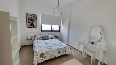 a white bedroom with a bed and a mirror at Modern 2BR -5MIN to Metro & Festival Mall- 1211 in Dubai