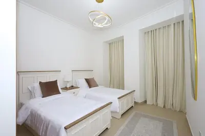 a white bedroom with two beds and a window at Lux 2 Bed in Downtown Dubai w Dubai Mall Access in Dubai