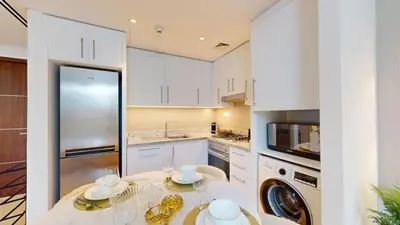 a kitchen with white cabinets and a table with dishes at Boulevard Point - One Bed with Burj Khalifa View in Dubai