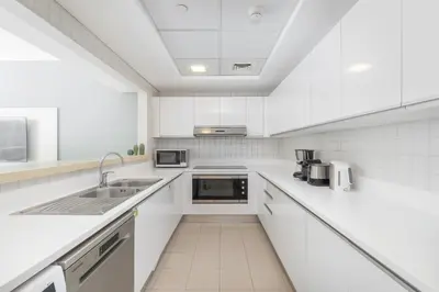 a white kitchen with white cabinets and a sink at Lavish 3BR Apartment with Pool Access in Al Bateen in Dubai