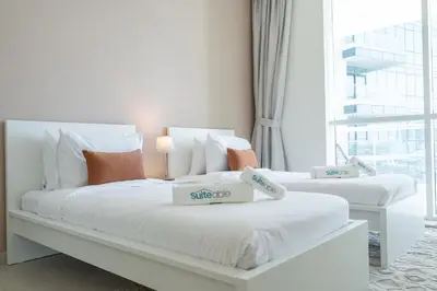 two white beds in a room with a window at Lavish 3BR Apartment with Pool Access in Al Bateen in Dubai
